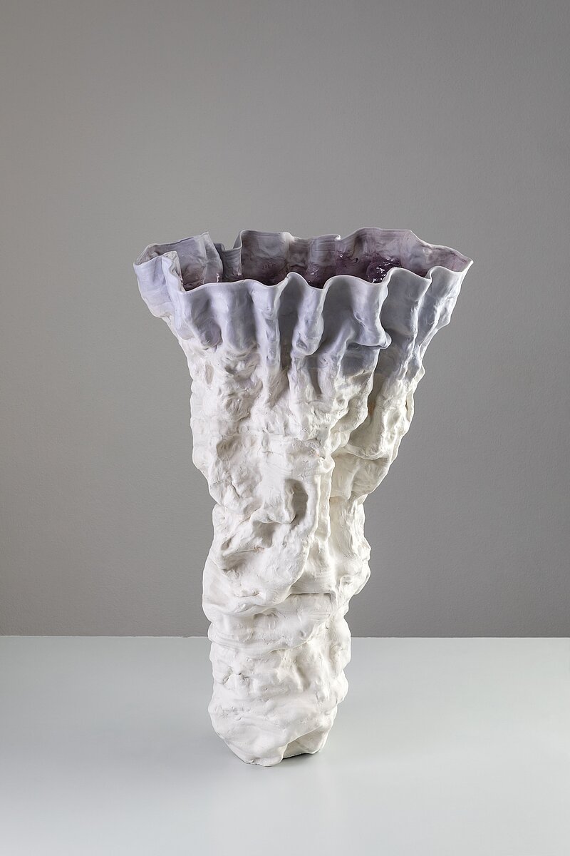 Foto einer weißen und lilafarbenen Porzellanvase mit unregelmäßig gewellter Oberfläche.