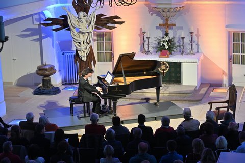 Zwei Pianisten spielen auf einem Flügel in einer Kirche