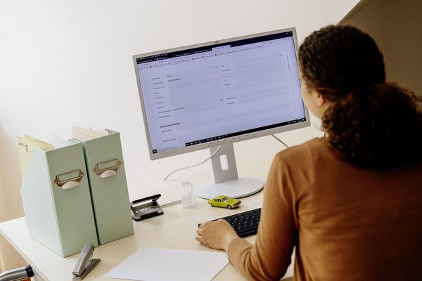 Eine Frau füllt ein Formular am Computer aus. 