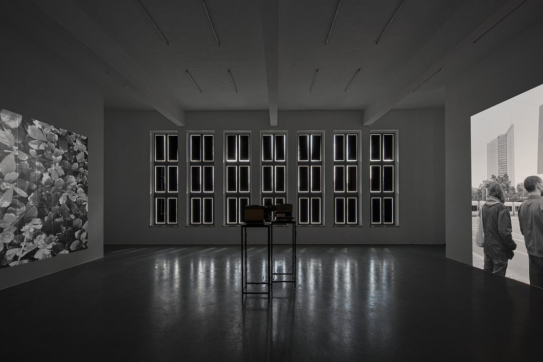 Ein dunkler Raum mit schwarz-weiß Projektionen an den gegenüberliegenden Wänden links und rechts.