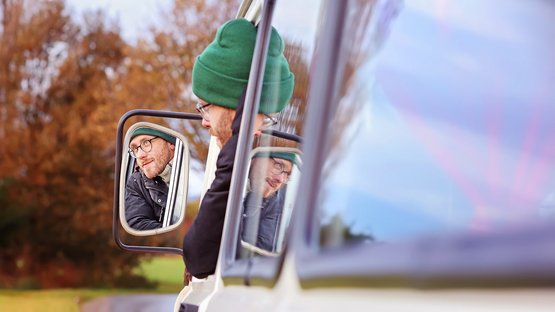 Matthias Ditscherlein sitzt auf dem Fahrersitz des Inselkinos. Das Bild fängt sein Spiegelbild aus dem Außenspiegel ein.