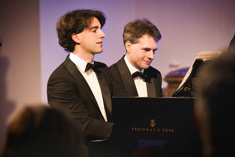 Zwei Pianisten spielen gemeinsam an einem Flügel. 