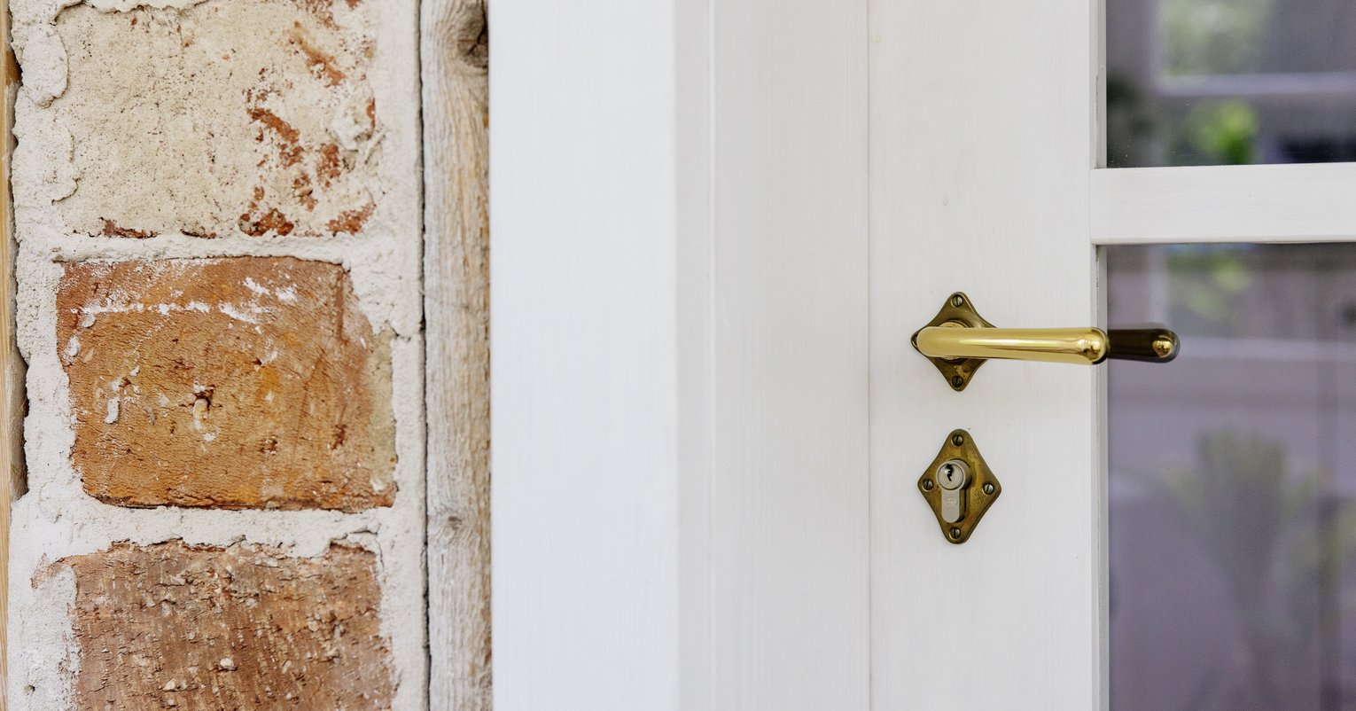 Nahaufnahme einer bronzenen Türklinge an einer weißen Tür.