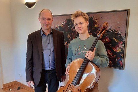 Johannes Schiel steht neben Rafael Knappe zur Übergabe des Cellos aus dem Musikinstrumentenfonds.