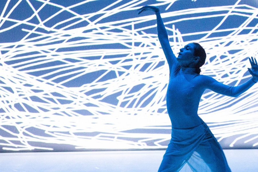 Eine Lichtkonstellation in Blau und Weiß mit einer tanzenden Frau im Zentrum.