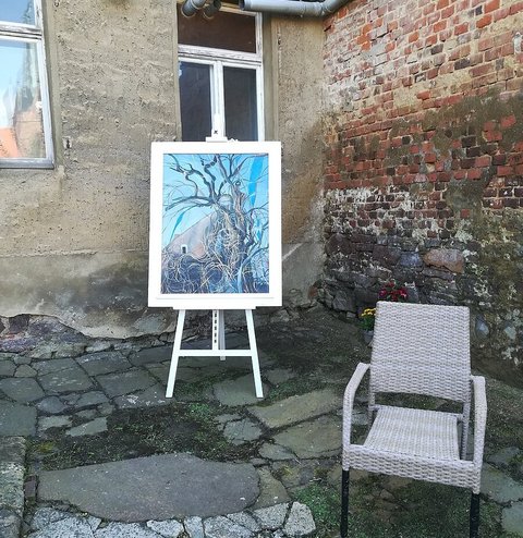 Ein Gemälde steht auf einer Staffelei in der Ecke eines Innenhofes.