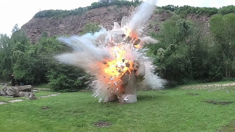 Standbild eines Videos, das die Explosion einer überdimensionalen Hasenfigur auf einer Wiese zeigt. 
