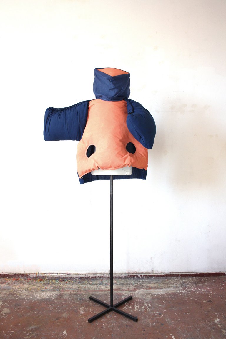 Dreidimensionaler Oberkörper geformt aus blauen und orangenen Textilien sowie Füllmaterial auf einer Kleiderpuppe. 