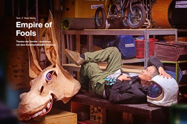 Das Bild zeigt eine Seite des Kulturstifters (Bookzine). Darauf ist ein Mann zu sehen, der in einer Garage auf einer Werkbank liegt. Neben ihm ein gebastelter Pferdekopf.